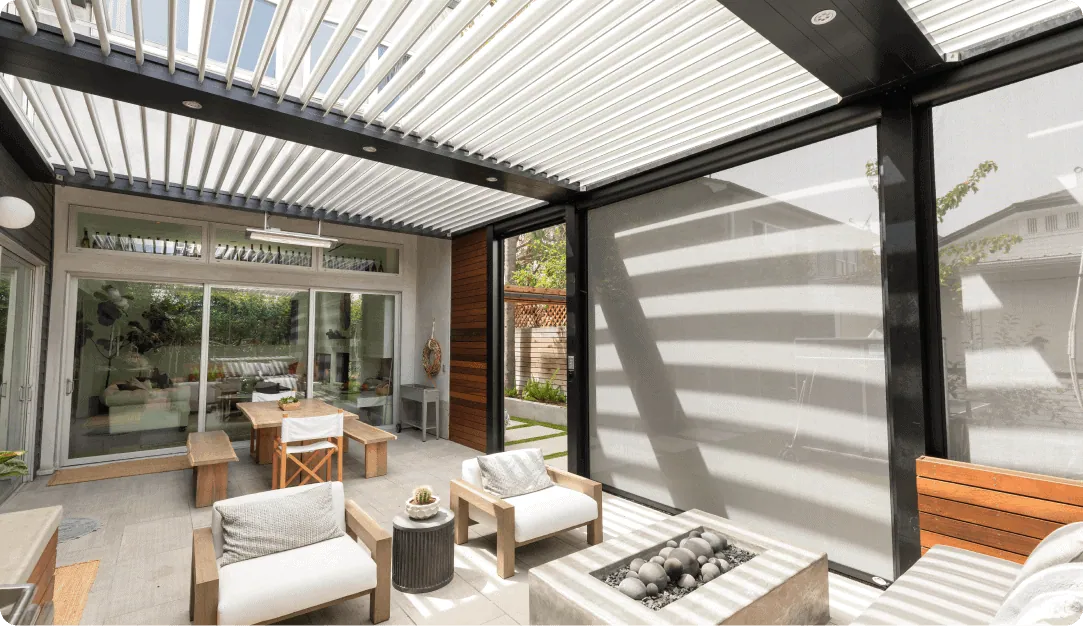 White louvered pergola over a lounge patio with a fire table and a retractable screen