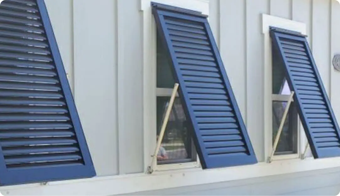 Three navy Bahama shutters propped open over white-trimmed windows