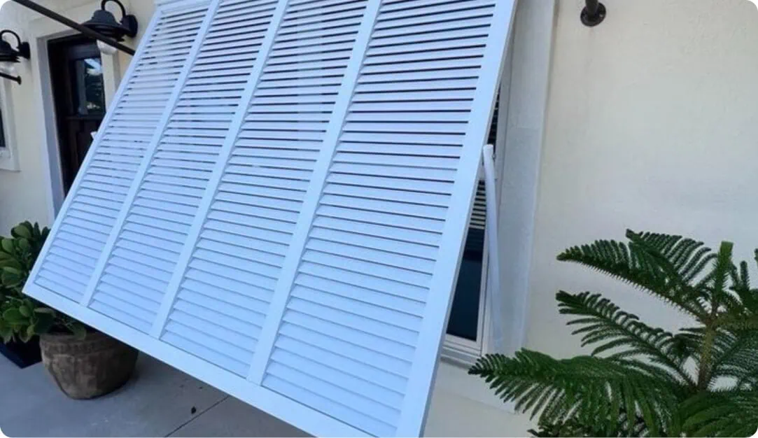 Close-up of a white Bahama shutter propped open beside an entry