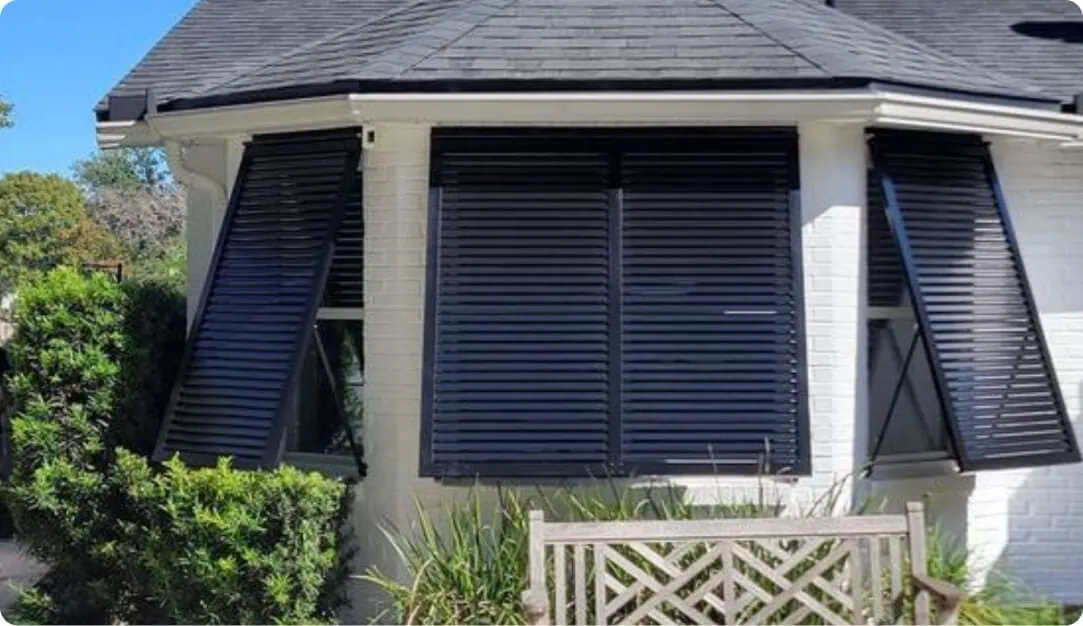 Navy Bahama shutters on the bay window of a white home