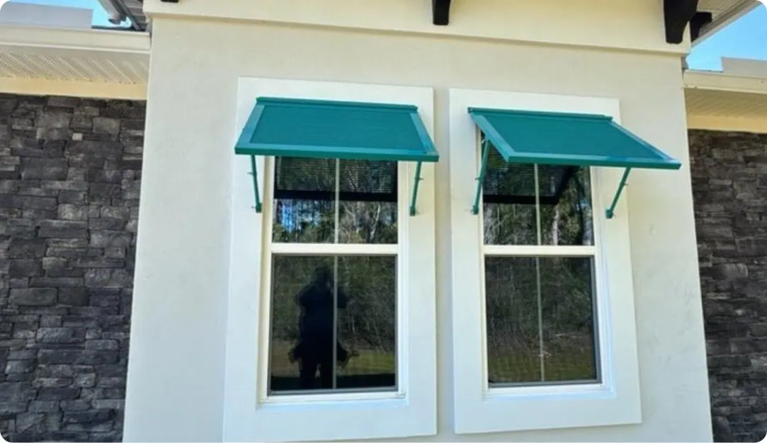 Teal Bahama shutters over two windows on a cream stucco home
