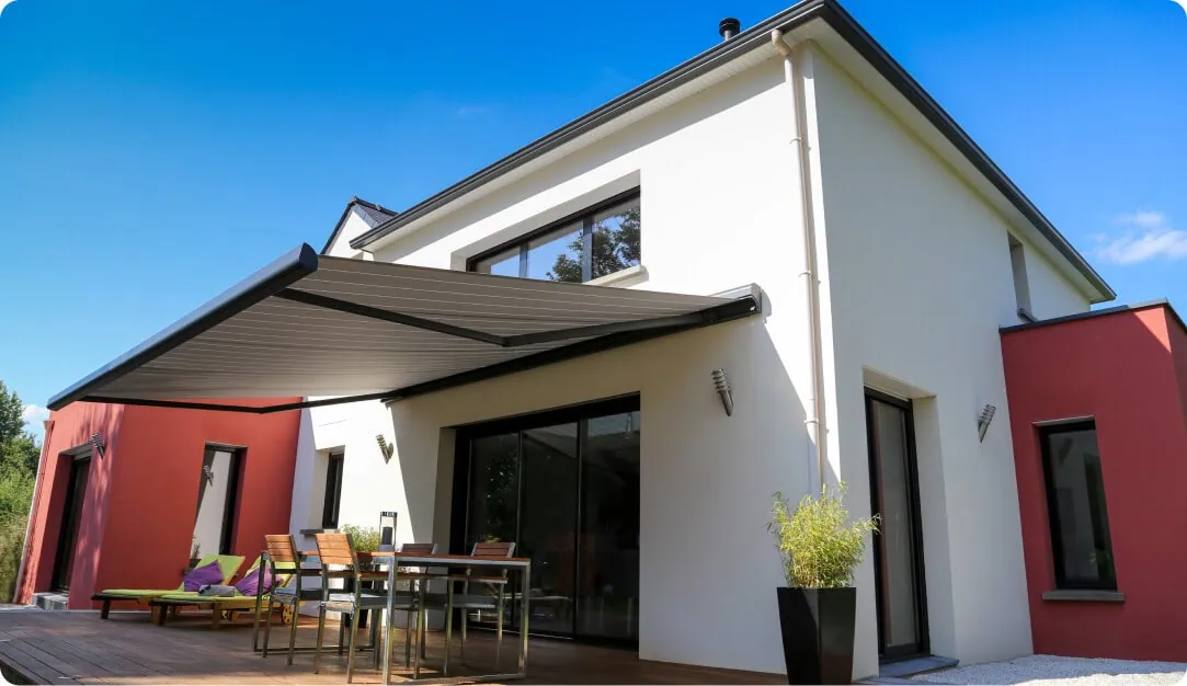 Dark gray retractable awning shading the patio of a modern white home