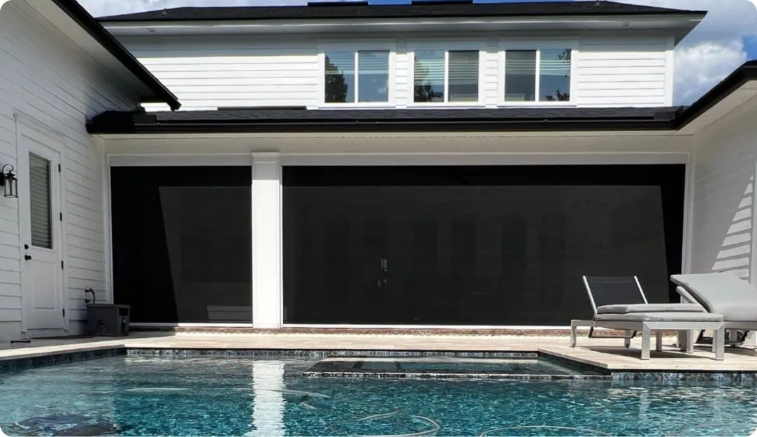 Black retractable screens lowered on a covered patio beside a pool